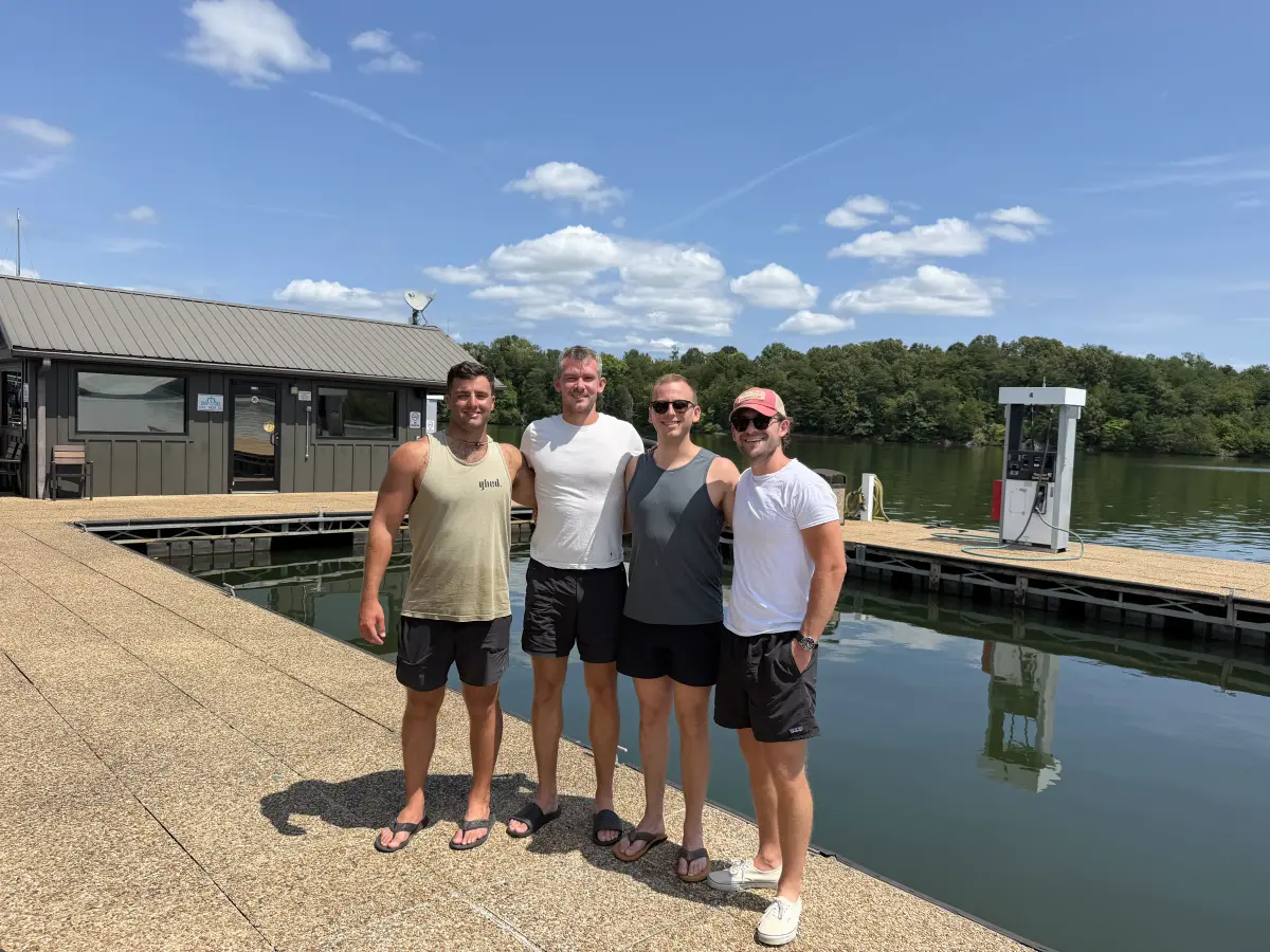 Four friends standing beside a boat dock